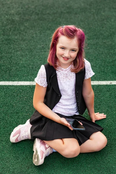 Leende Skolflicka Med Rosa Hår Skoluniform Sitter Det Gröna Golvet — Stockfoto