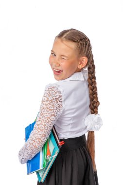 Beyaz bluzlu bir öğrenci elinde kitaplar ve defterler, gülümsemeler, göz kırpmalar tutuyor. Okul üniformalı bir kız. Stüdyo fotoğrafı, beyaz arka planda izole edilmiş. eğitim
