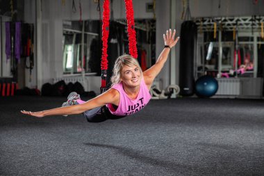 Bungee fitness. Döngüler üzerinde çalışıyorum. Pembe eşofmanlı güzel bir spor kadın spor salonunda özel döngülerin yardımıyla antrenman yapıyor. Araf 'ta pozlar