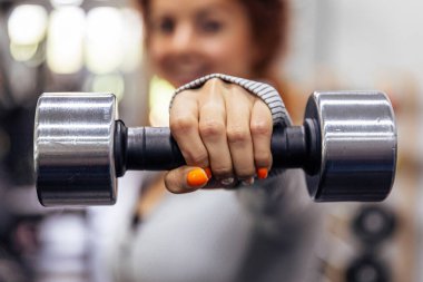 Yakın plan: Bir kadının elindeki dambıl, yüzü dağılmış haldeydi.