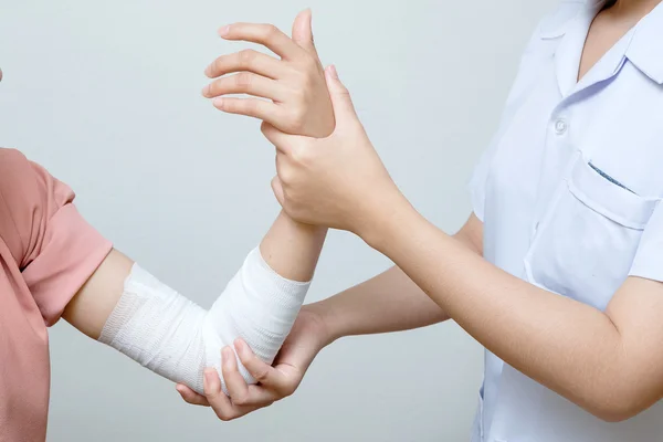 Enfermeira aplicando bandagem ao paciente cotovelo lesionado — Fotografia de Stock