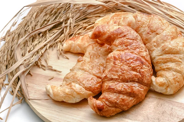 Delicious fresh croissants with rice on wooden background — Stock Photo, Image