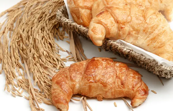 Delicious fresh croissants with rice on wooden background — Stock Photo, Image