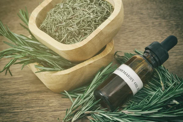 Rosemary essential oil in bottle and fresh rosemary on old woode — Stock Photo, Image