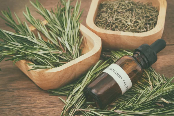 Rosemary essential oil in bottle and fresh rosemary on old woode — Stock Photo, Image