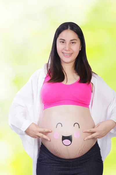 Mulher grávida feliz com rosto sorridente em sua barriga — Fotografia de Stock