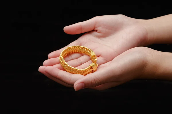 Mains de fille avec des bracelets dorés sur un fond noir — Photo