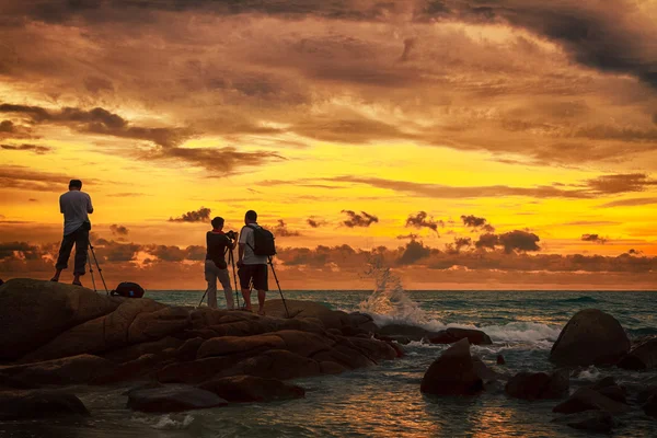 Valokuvaaja ottaa kuvia rannalla auringonlaskun aikana — kuvapankkivalokuva