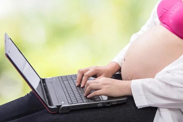 Молодая беременная женщина использует свой ноутбук — стоковое фото