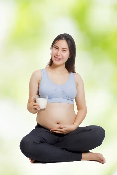 Těhotná žena drží a pije sklenici mléka — Stock fotografie