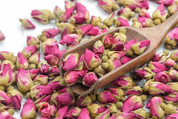 Closeup roses flowers tea in a wooden scoop on a white backgroun — Stock Photo, Image