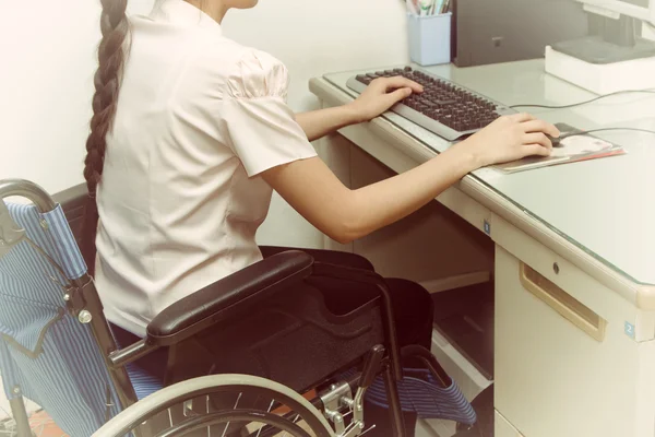 Asia woman in wheelchair working on computer in the office