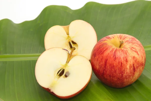 Свежее яблоко с ломтиком на банановом листе — стоковое фото