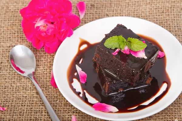 Brownie de chocolate en plato con pétalos de rosa — Foto de Stock