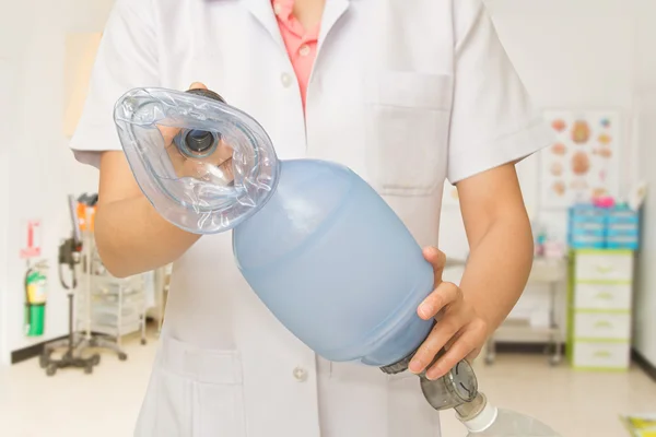 La mano del médico sostiene la bolsa de respiración con mascarilla facial para pacientes de ayuda — Foto de Stock