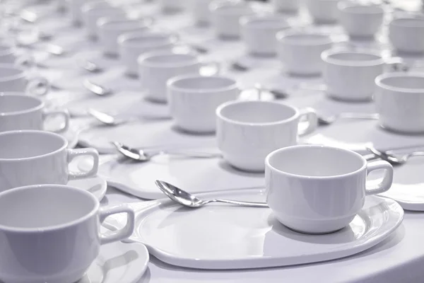 Montones de tazas de café con cucharaditas de plata se preparan para la meetina —  Fotos de Stock