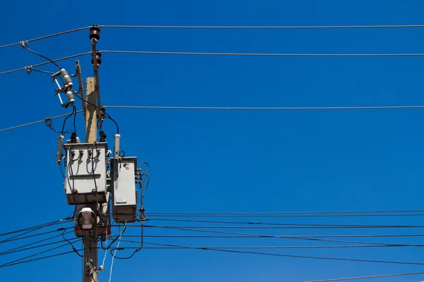 Poste eléctrico con cables de línea de alimentación en el cielo azul —  Fotos de Stock