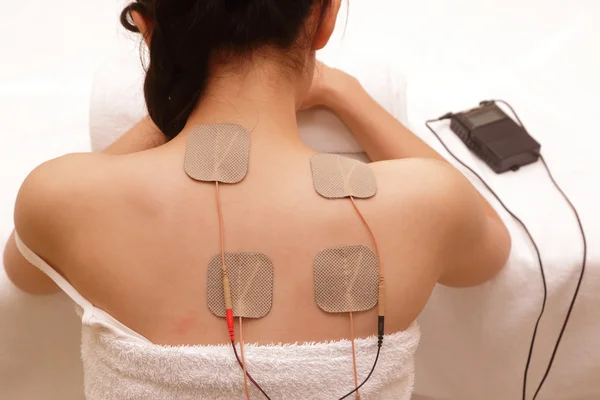 Mujer asiática está haciendo masaje de estimulación eléctrica (TENs  ) —  Fotos de Stock