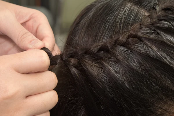 Парикмахер делает косички на длинных волосах — стоковое фото