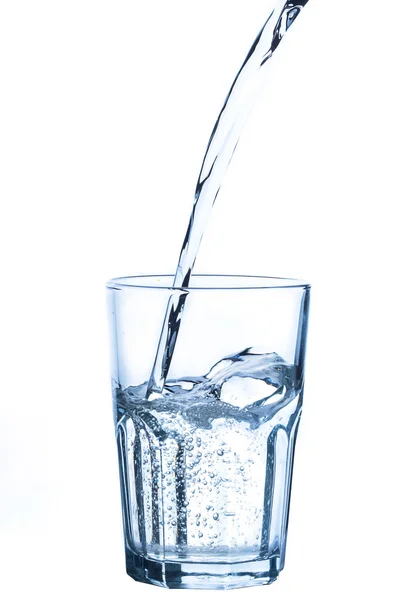 Gieten van water in glas op een witte achtergrond Rechtenvrije Stockfoto's