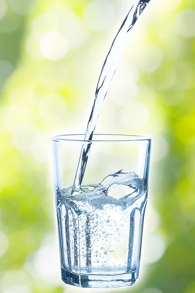 Versare acqua in vetro su fondo verde — Foto Stock