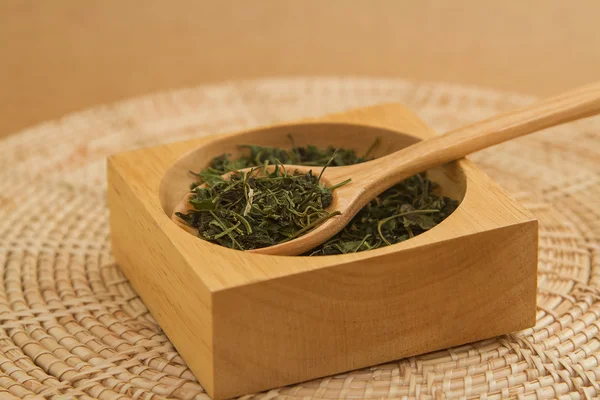 Hojas de té verde seco en cuchara de madera sobre fondo marrón . —  Fotos de Stock