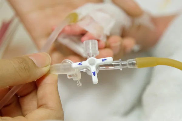 Mano del médico con goteo intravenoso insertado en la mano del paciente infantil — Foto de Stock