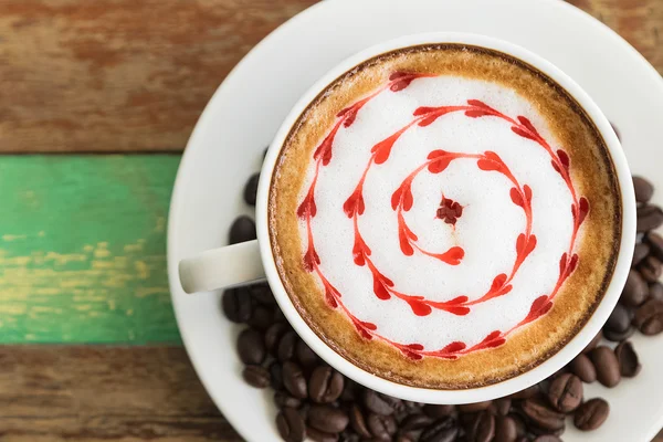 Latte τέχνη, καφέ με καφέ φασόλια σε ξύλινα φόντο — Φωτογραφία Αρχείου