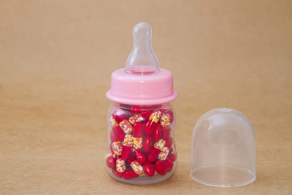 Pills in feeding bottle on brown background — Stock Photo, Image