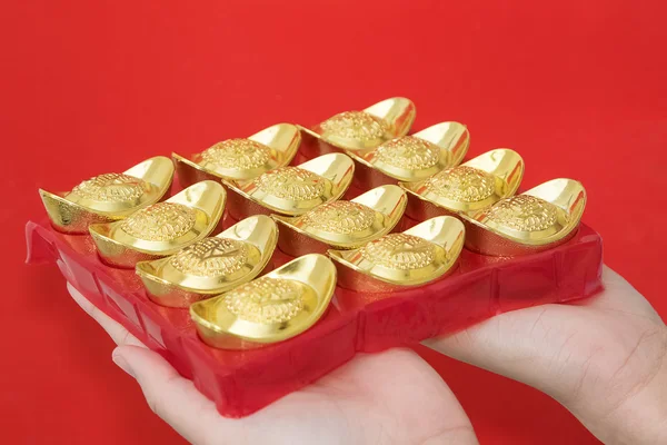 Hand giveing gold ingot to someone for Chinese New Year celebrat — Stock Photo, Image