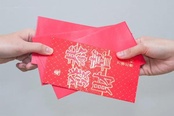 Woman hand giving red envelop containing money, with Good Luck c — Stock Photo, Image