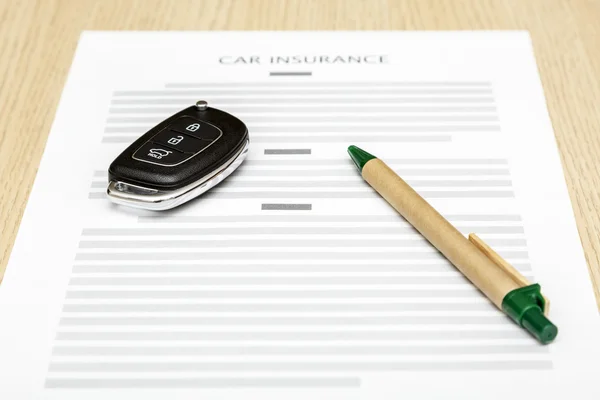 Car keys and pen laying on a blank of insurance. — Stock Photo, Image
