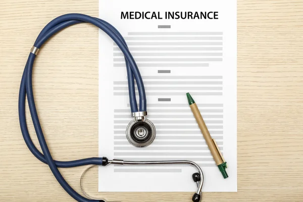 Stethoscope and pen laying on the blank of medical insurance. — Stock Photo, Image