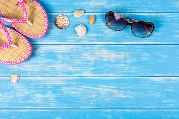 Вид солнцезащитных очков и флип-флопс, лежащих на голубом деревянном полу — стоковое фото