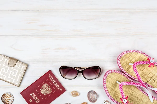 Паспорт, бумажник, солнцезащитные очки и шлепанцы на белом деревянном фоне . — стоковое фото