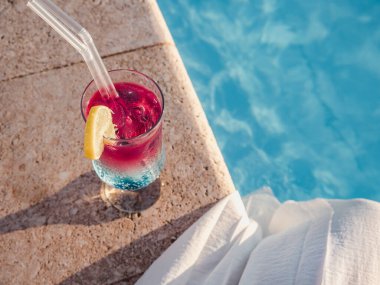 Havuzun arka planında kokteyl olan güzel bir bardak. Yukarıdan bak, yakın plan. Boş zaman ve seyahat kavramı