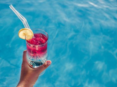 Havuzun arka planında kokteyl olan güzel bir bardak. Yukarıdan bak, yakın plan. Boş zaman ve seyahat kavramı