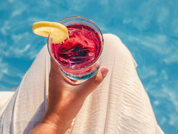 Beautiful glass with a cocktail on the background of the pool. View from above, close-up. Concept of leisure and travel