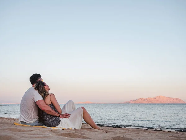 英俊的男人和可爱的女人坐在沙滩上 有着大海的背景 休闲和旅行的概念 — 图库照片