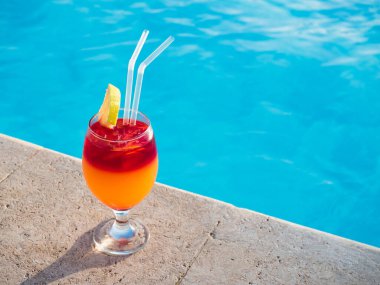 Havuzun arka planında kokteyl olan güzel bir bardak. Yukarıdan bak, yakın plan. Boş zaman ve seyahat kavramı