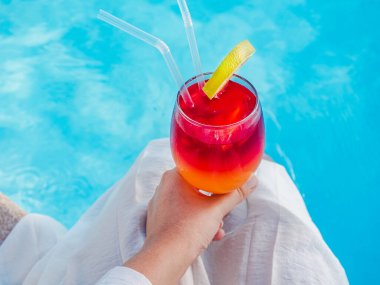 Havuzun arka planında kokteyl olan güzel bir bardak. Yukarıdan bak, yakın plan. Boş zaman ve seyahat kavramı