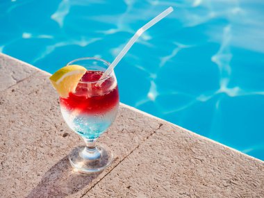 Havuzun arka planında kokteyl olan güzel bir bardak. Yukarıdan bak, yakın plan. Boş zaman ve seyahat kavramı