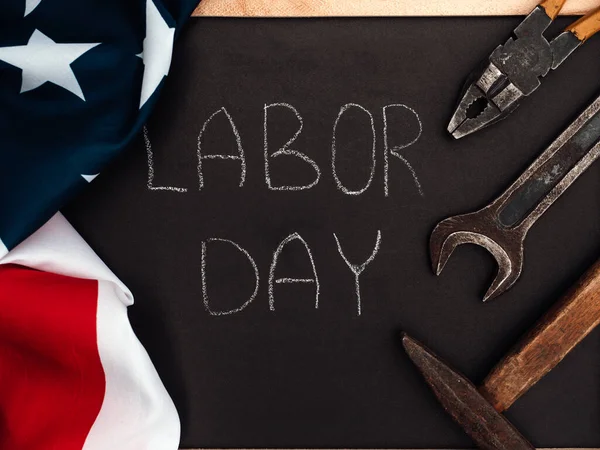 LABOR DAY. Hand tools and the Flag of the United States of America lying on the table. View from above, close-up. Congratulations to family, relatives, friends and colleagues. National holiday concept