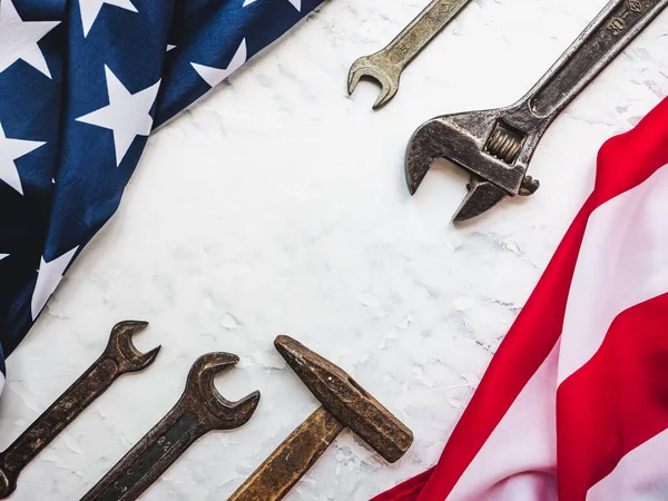 LABOR DAY. Hand tools and the Flag of the United States of America lying on the table. View from above, close-up. Congratulations to family, relatives, friends and colleagues. National holiday concept