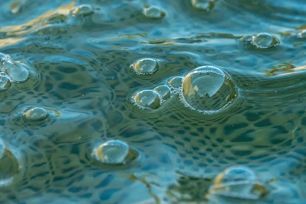 Su yüzeyinde hava kabarcıkları. Temiz mavi suda oksijen makro kabarcıklar oluşturur. Konseptler, ekoloji, çevre, temiz deniz, içme suyu