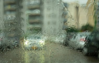 Şiddetli bir sonbahar gününde arabanın ön camından geçen trafiğin bulanık görüntüsü.