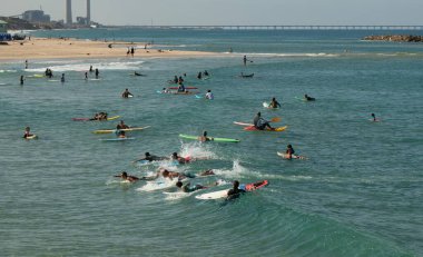 Her yaştan çok ırklı bir grup erkek ve kız çocuğu güneşli bir gökyüzü ve denizin zemininde sörf yapıyor, İsrail, Ashkelon, 13 Kasım 2020.