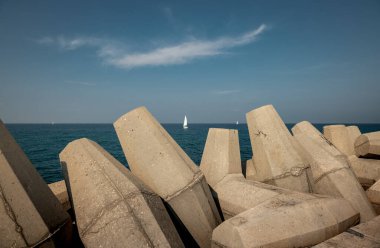  Akdeniz kıyısı. Beton levhaların arasından beyaz bir yelkenliye bak. İsrail Ashkelon Kasım 2020