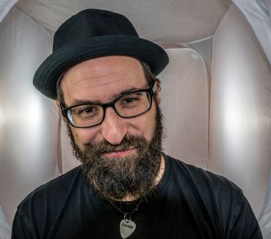 Siyah gözlüklü, neşeli, gülümseyen bir adam.