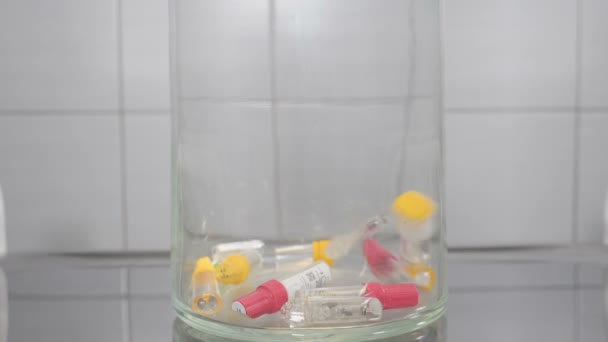 Современная концепция стоматологии. Пустые контейнеры имплантата падают в замедленной съемке в стеклянной чаше символизируя много работы и много пациентов в занятом стоматологическом кабинете. Полный список — стоковое видео